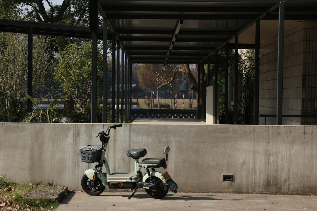 White electric scooter parked beside a concrete wall